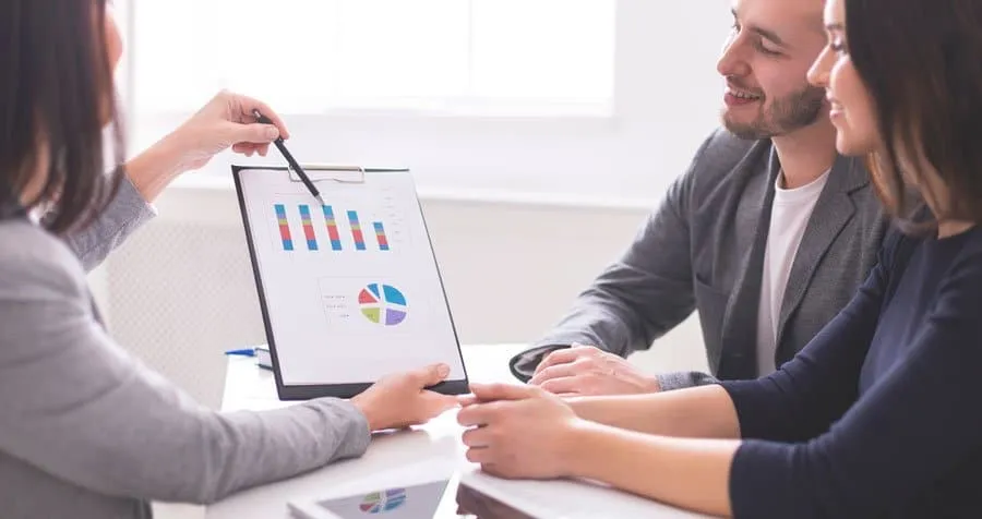 Couple seated at a desk reviewing a chart with an adviser