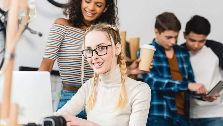 Teenage girl with glasses smiling with friends in a classroom