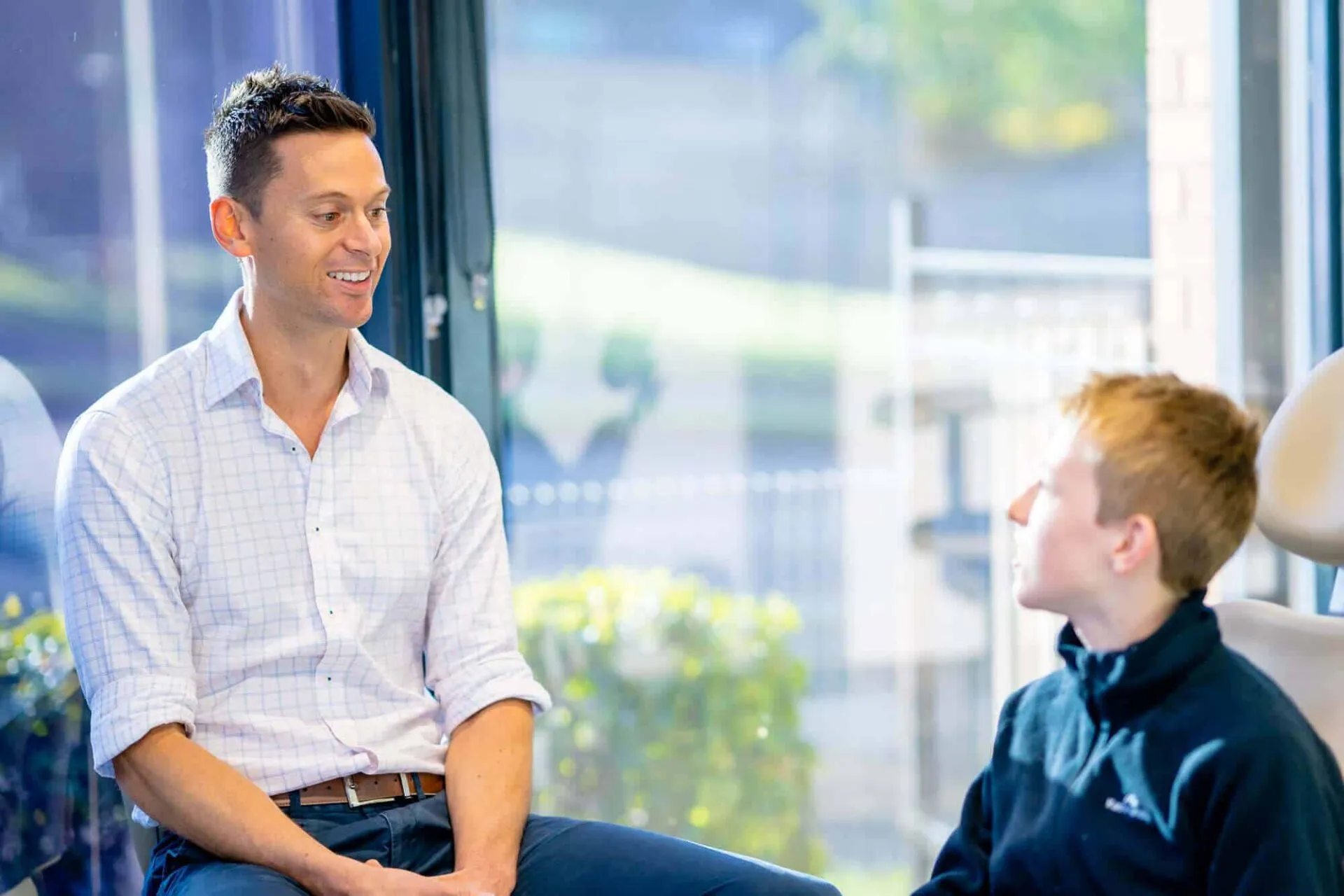Orthodontist talking with a teenage boy in a consultation room at Central Coast Orthodontics