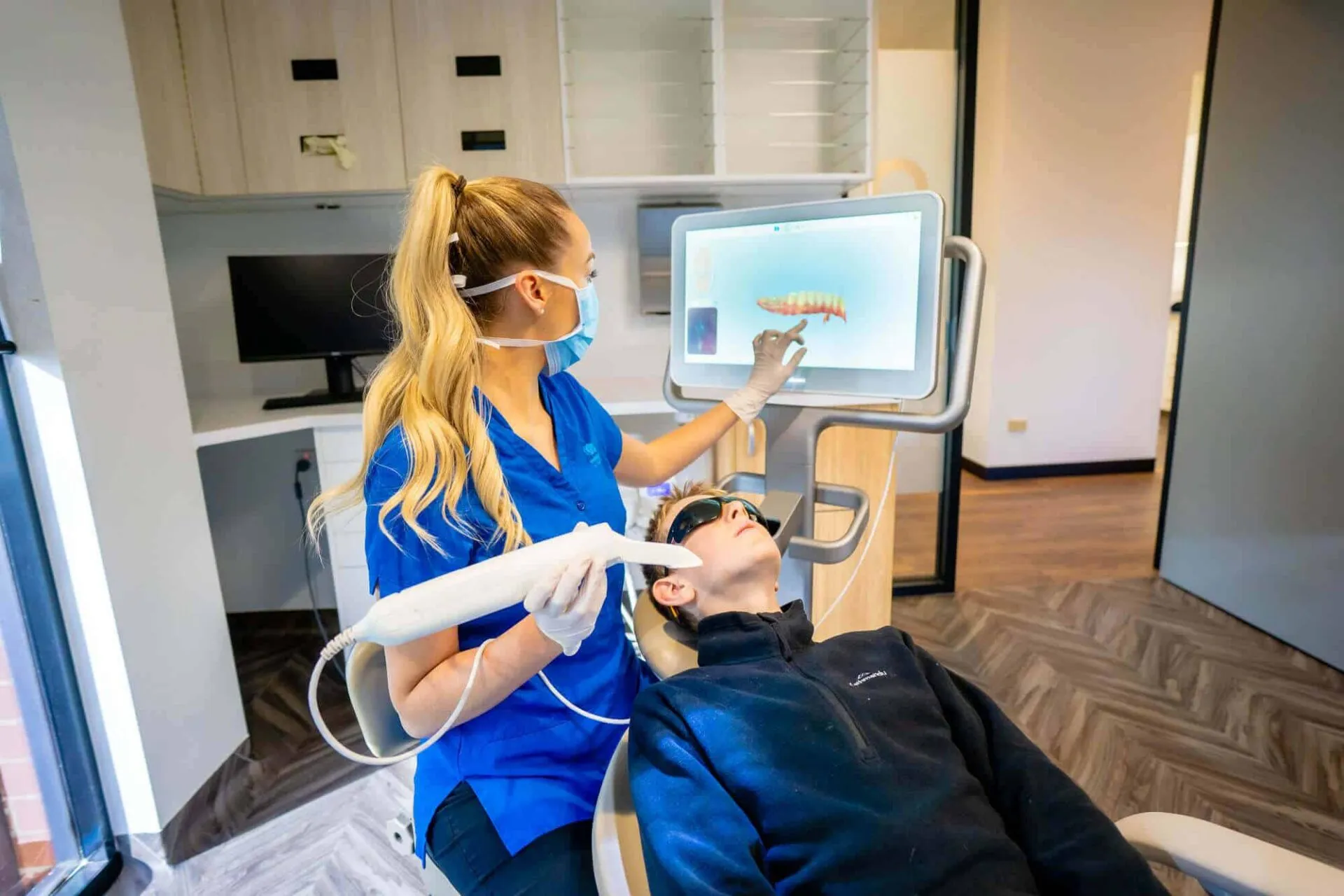 Dental assistant scanning a patient's teeth with a digital intra-oral scanner in the treatment room