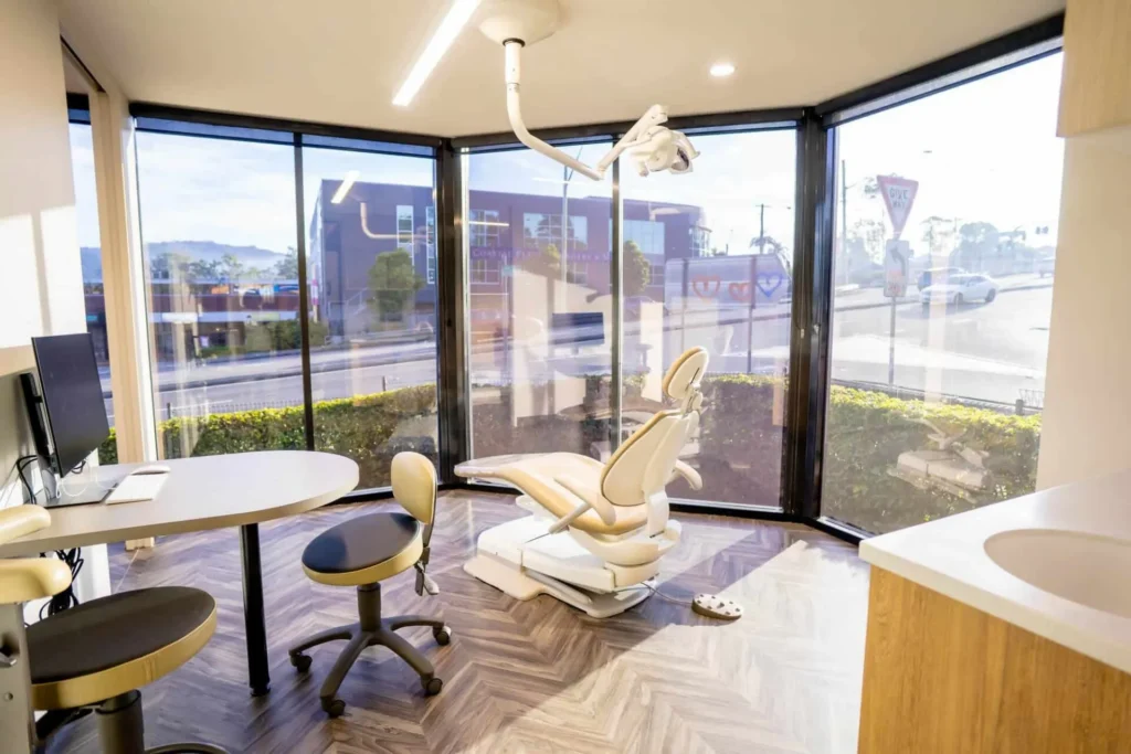 Corner consultation room with floor-to-ceiling windows and a dental chair