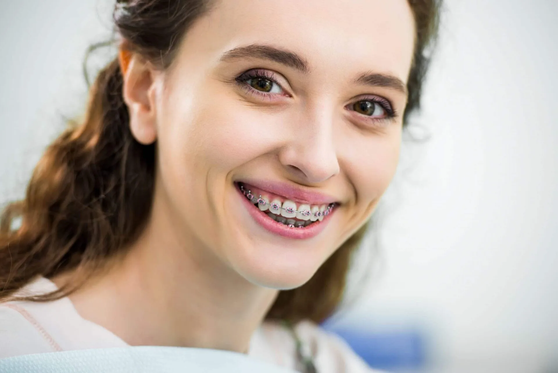 Close-up of a smiling young woman wearing metal braces