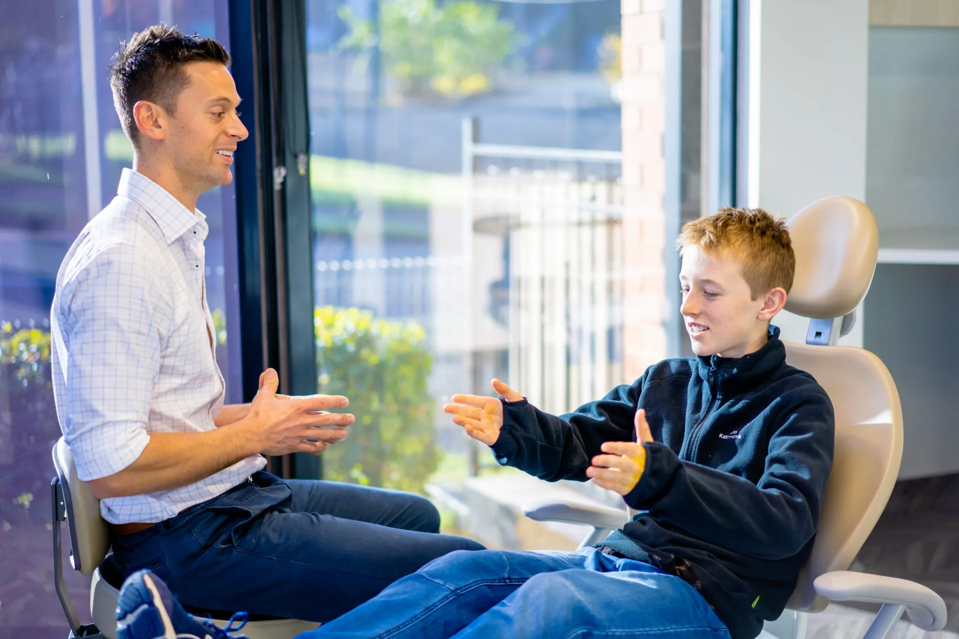 Orthodontist in conversation with a teenage boy in the treatment room
