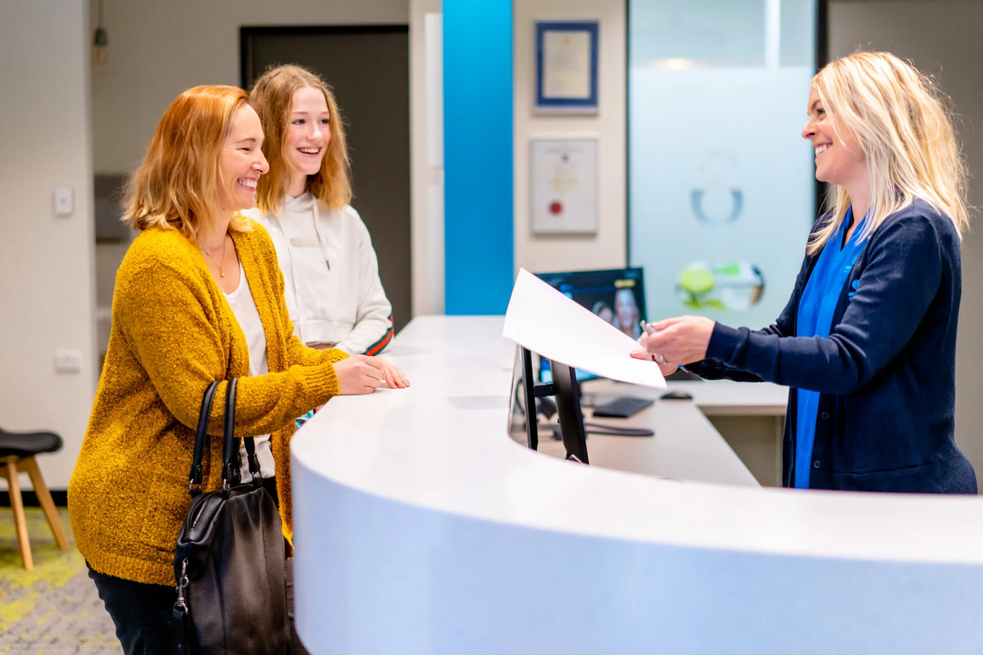 Two patients being greeted by a receptionist at the Central Coast Orthodontics front desk