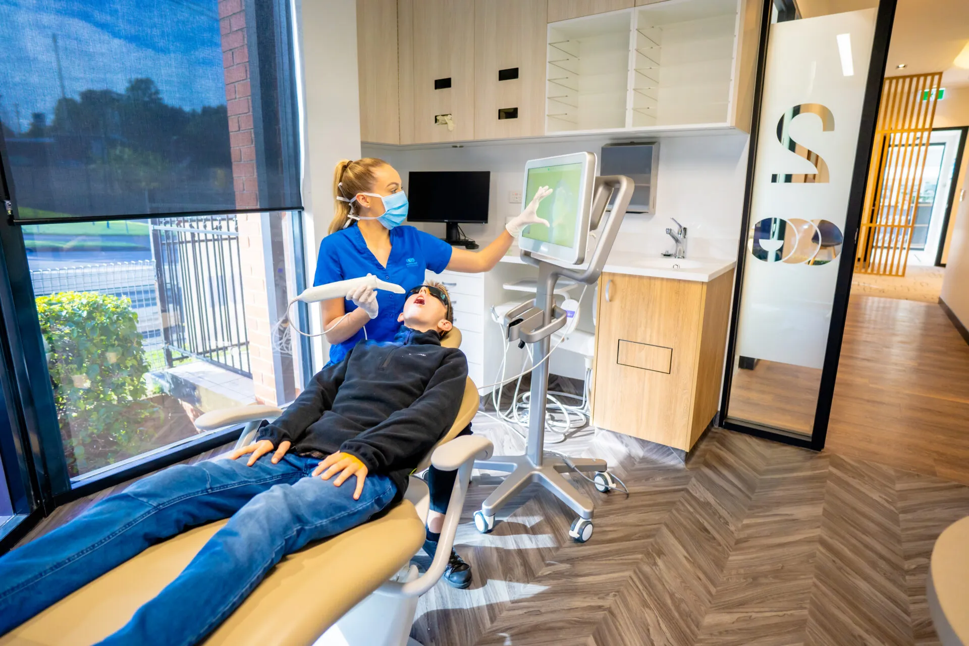 Dental assistant treating a patient in the chair beside the window at Central Coast Orthodontics