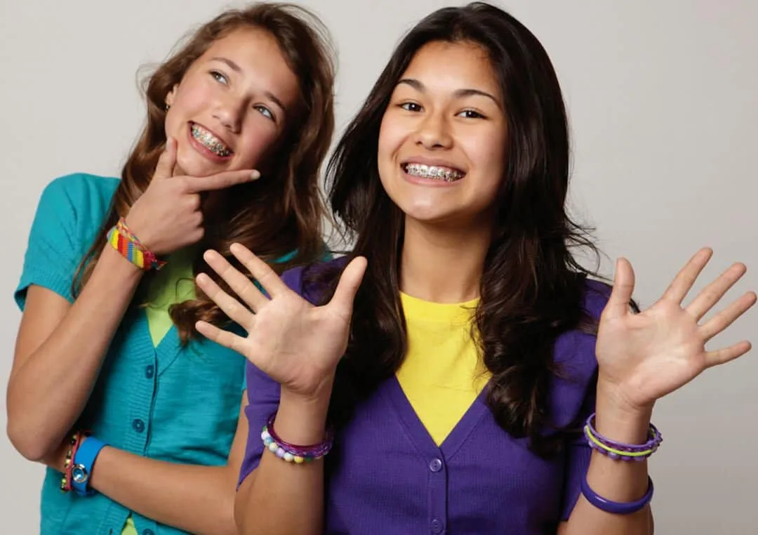 Two smiling teenage girls, one of them wearing braces