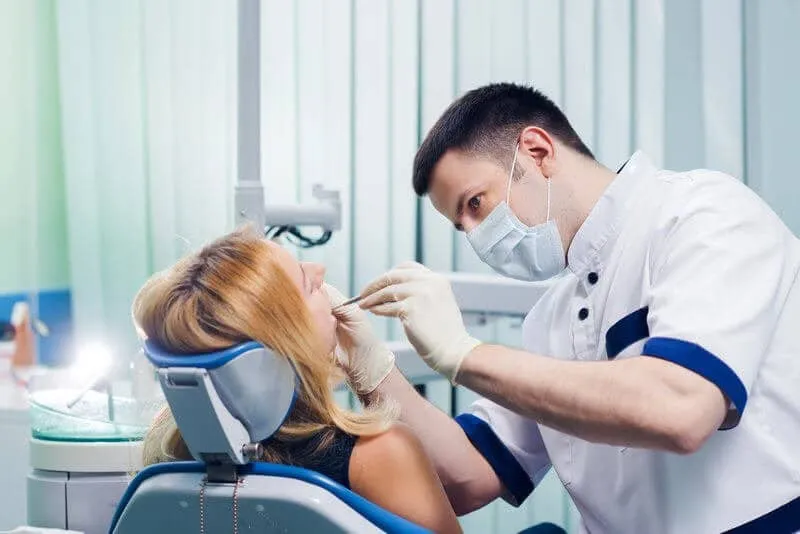 Clinician in a mask treating a patient reclined in the dental chair