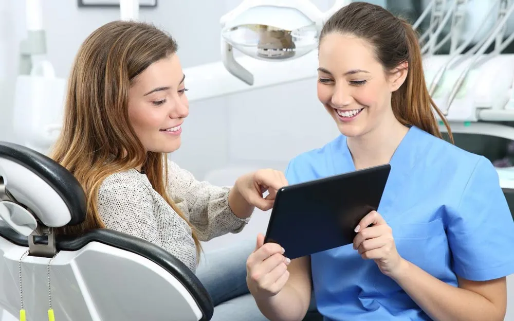 Dental nurse showing a tablet to a patient seated in the treatment chair