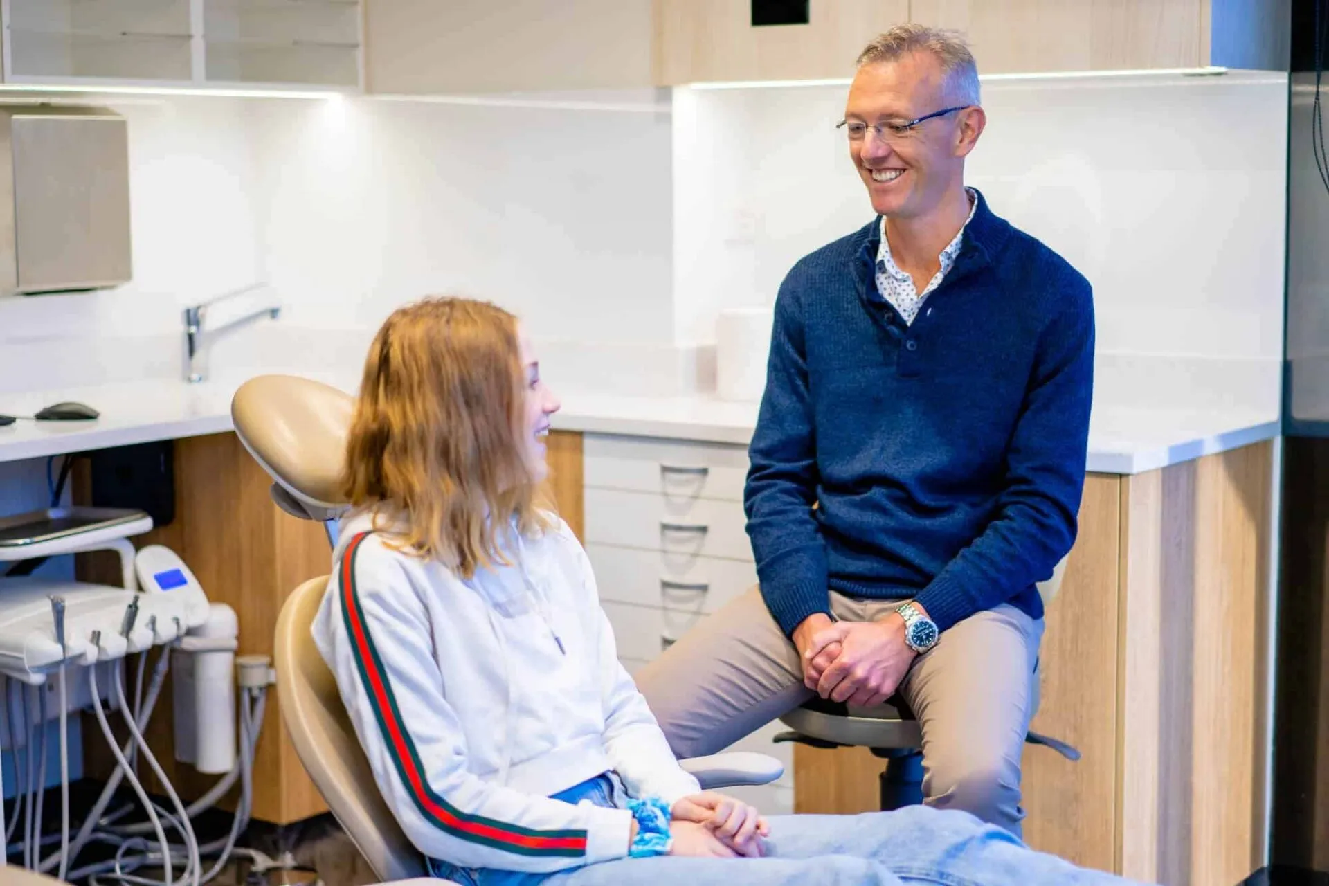 Orthodontist smiling with a young patient in the treatment room