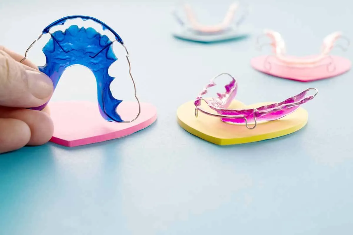 Several coloured removable orthodontic retainers laid out on a bench