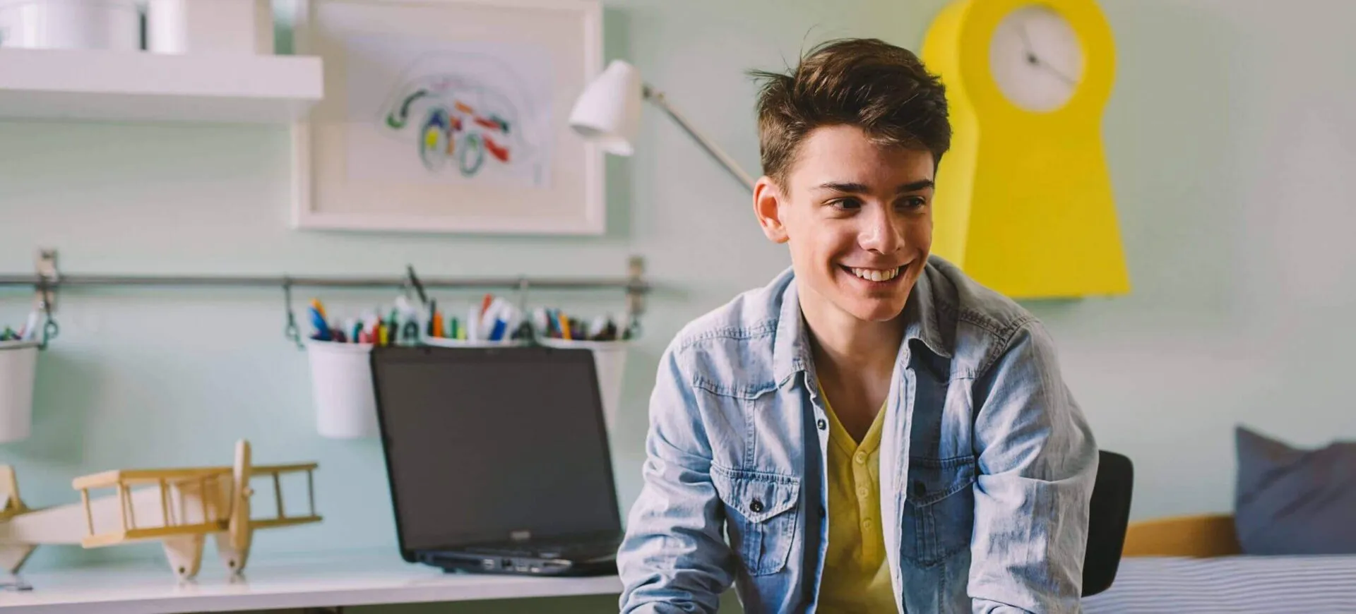 Teenage boy smiling at a desk with a laptop