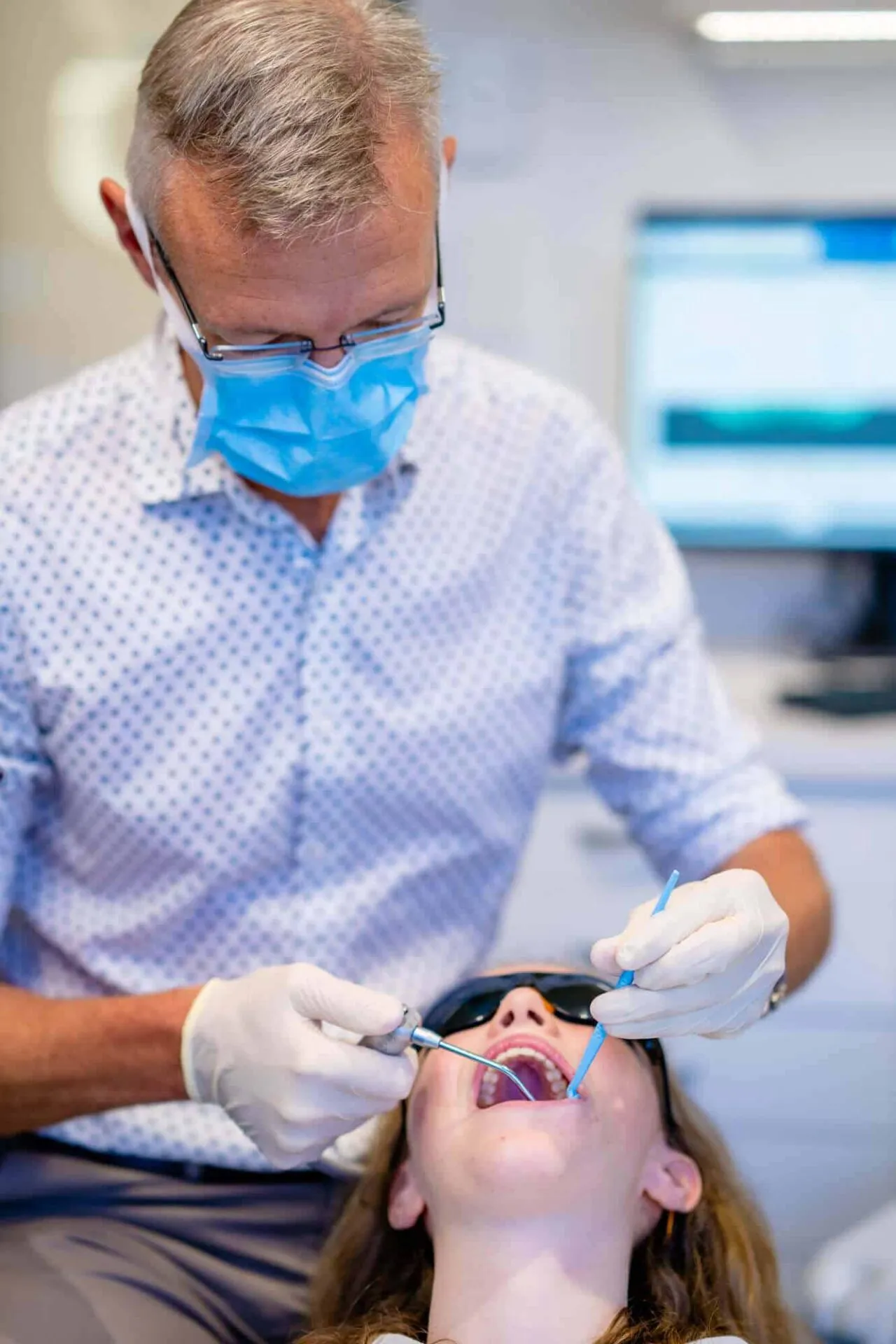 Orthodontist wearing a mask fitting an appliance in a patient's mouth