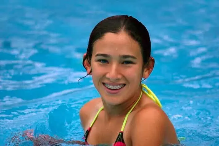 Teenage girl with braces smiling in a swimming pool
