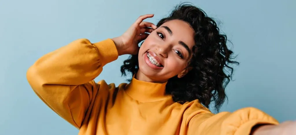 Smiling woman in a mustard jumper against a blue background