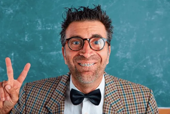 Man in glasses and a bow tie smiling with braces and making a peace sign