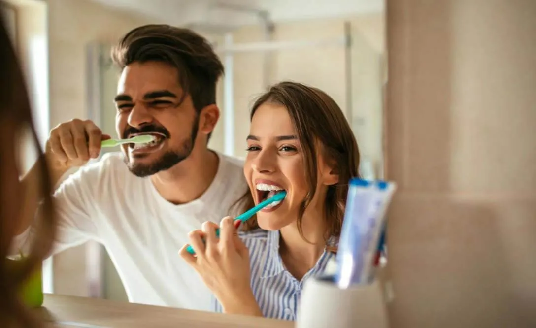 Man and woman brushing their teeth together at the bathroom mirror