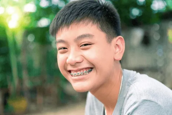 Boy with braces smiling outdoors