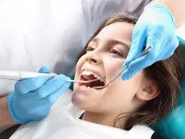Young girl in the dental chair having her teeth examined with a mirror and probe