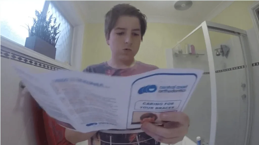 Teenage boy reading a Central Coast Orthodontics information booklet