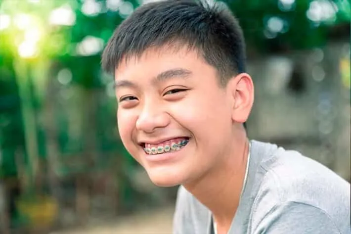 Boy with braces smiling outdoors