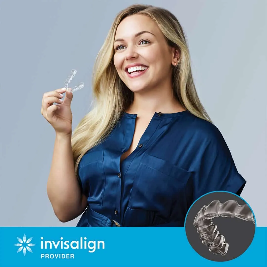 Smiling woman holding a clear Invisalign aligner