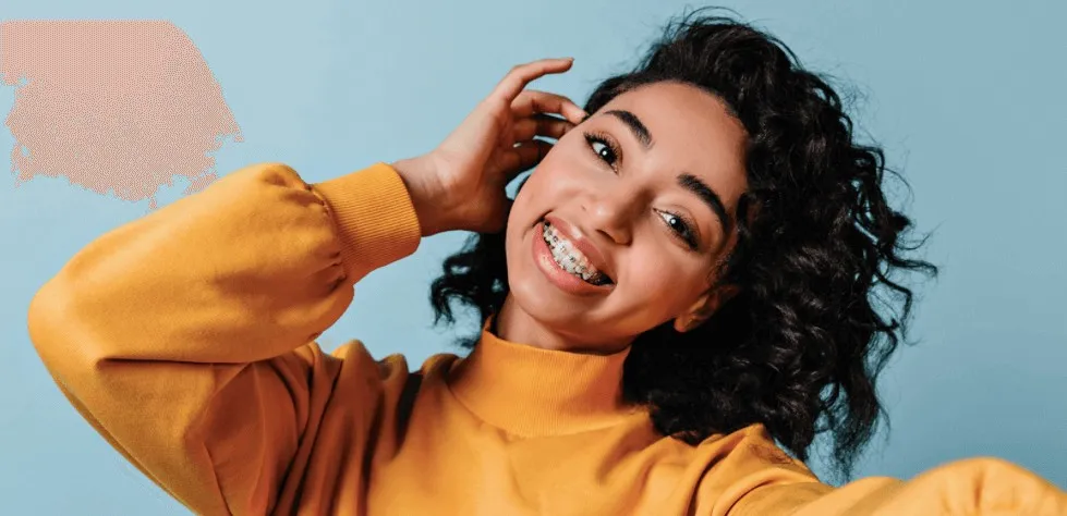 Smiling woman in a mustard jumper against a blue background